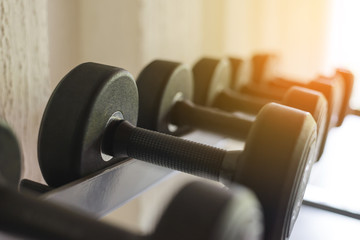 Rows of black dumbbell set on rack in the gym. Weight Training Equipment. Health care concept.