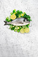 Fresh sea Bream fish on herbs and spices - preparing for cooking on white background. The concept of healthy food, top view and copy space.