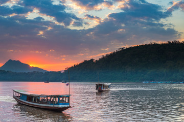 Boats on Mekong River at Luang Prabang Laos, sunset dramatic sky, famous travel destination backpacker in South East Asia