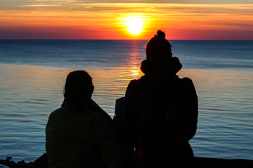 Mom and daughter see the sunset off the sea