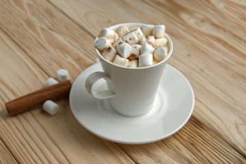 Hot morning coffee with marshmallow and cinnamon on a wooden stand, top view