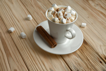 Hot morning coffee with marshmallow and cinnamon on a wooden stand, top view