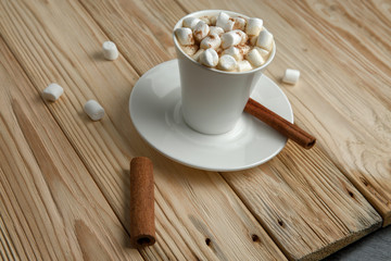 Hot morning coffee with marshmallow and cinnamon on a wooden stand, top view