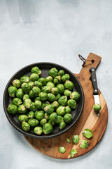 flat lay, Brussels sprouts on black plate, wooden cutting board