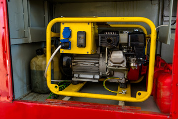 Power generator for gasoline in a yellow housing standing in the glove compartment of a fire truck.