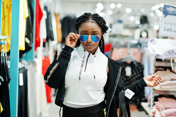 Afican american women in tracksuits and sunglasses shopping at sportswear mall with sport bag against shelves. Sport store theme.