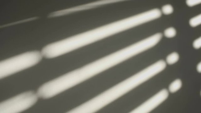 Shadows on the wall of an electric window shutter being opened in room
