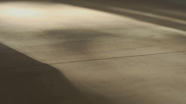 Shadow of a man walking back and forth on wooden parquet floor