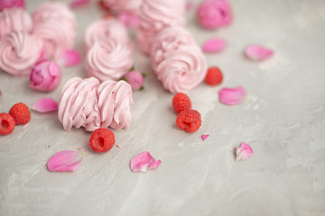 Rose and rose petals, raspberries, homemade pink marshmallows on a concrete background