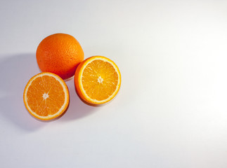 Two halves and one whole juicy orange closeup on a white background. Top view. Copy space.