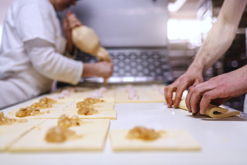 Caucasian hardworking bakers making rolls with jam. Bakehouse interior.