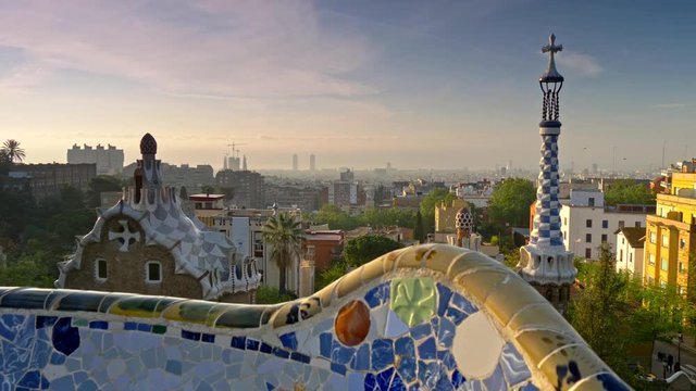 Crane shot of Barcelona city view from Guell Park. Sunrise view of colorful mosaic building in Park Guell. UHD, 4K