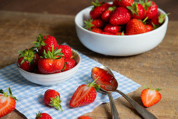 erdbeeren in weißen schalen mit erdbeermarmelade auf dem löffel