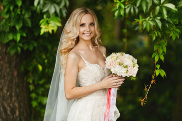Bouquet of fresh flowers in the hands of the young beautiful woman with blond hair and in the wedding dress