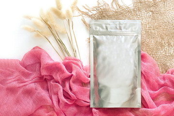 Foil packaging for loose cosmetic products, with a pink sticker, cloth and dried flowers, natural...
