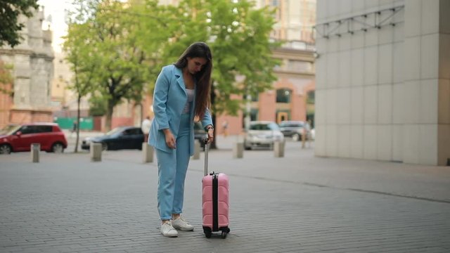 Woman have a typical problem with her suitcase in city, the handle does not slide out
