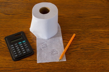 Incorrect calculations on white toilet paper isolated on a wooden surface conceptual image with copy space in landscape format