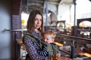 Mother with ergobaby carrying toddler in cafe
