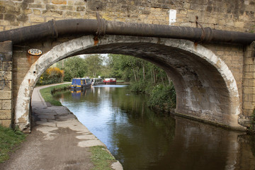 Just beyond the old stone bridge on the Leeds and Liverpool Canal at Dowley Gap, Yorkshire, boats are tied up for the night