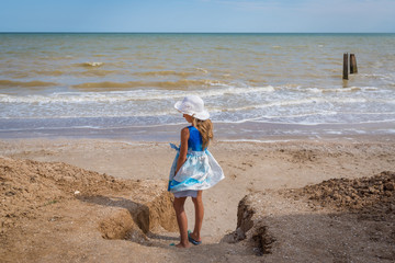 Beautiful seascape. The girl in a dress and a white hat goes down to the sea