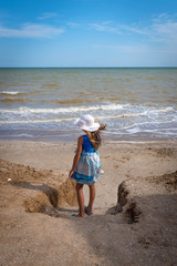 Beautiful seascape. The girl in a dress and a white hat goes down to the sea