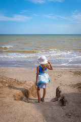 Beautiful seascape. The girl in a dress and a white hat goes down to the sea
