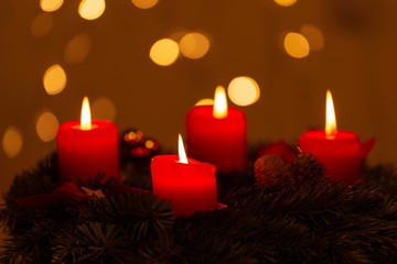 Four burning red Advent candles with bokeh