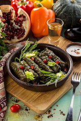 A plate of delicious stuffed grape leaves with ground meat and pomegranate on wooden board