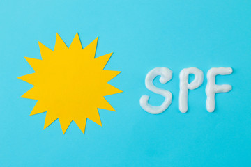 the inscription SPF from cream and the sun from paper on a bright blue background. Sun protection concept. Ultraviolet protection. Summer. Vacation .. top view