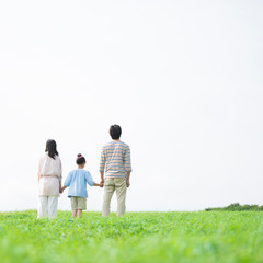 草原で手をつなぐ家族の後姿