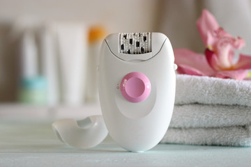 A modern epilator on the background of the bathroom interior.