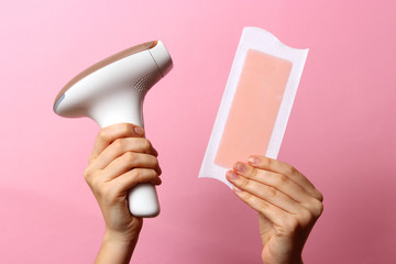 Home modern photo of epilator and wax strip in female hands on color background. Untreated hair removal.