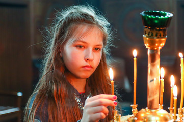 little girl puts a candle in church. Orthodoxy and children