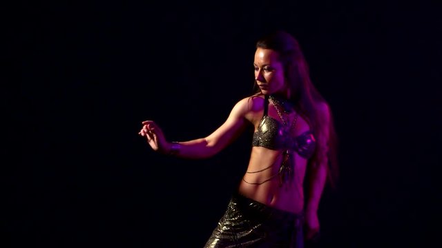 Slender woman dancing belly dance in a dark Studio. Black background. Slow motion