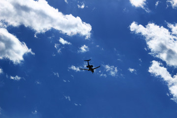 A jet airliner flying under the sun shining in the sky