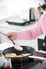 Home kitchen. An old woman frying pancakes