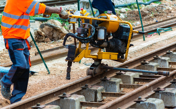 Railway workers bolting track rail. Detail worker with mechanical bolting wrench