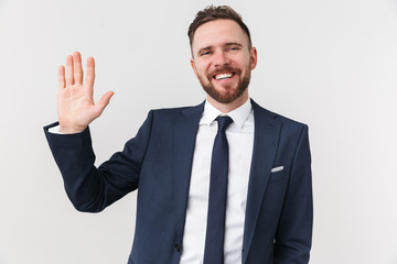 Happy young businessman posing isolated over white wall background waving.