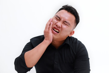 Young man suffering from toothache on white background, closeup