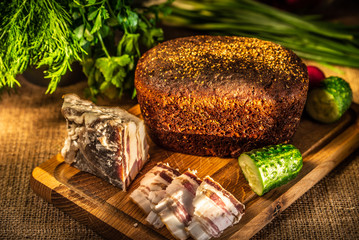 Rye bread, lard and radish on a wooden board in the rays of sunlight.
