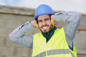 construction worker or engineer covering his ears