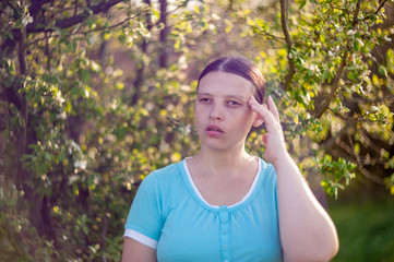 Portrait of happy girl in blue blouse on background of bright spring foliage in sunlight of sunset. Natural light effects lens. Selective focus, shallow depth of field. Artistic image of nature, bokeh