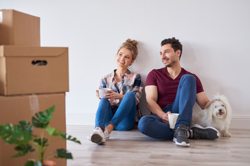 Smiling couple with coffee cups relaxing in their new home