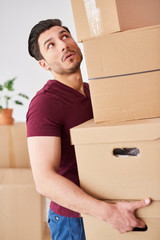 Obraz na płótnie Canvas Stressed man carrying stack of cardboard boxes