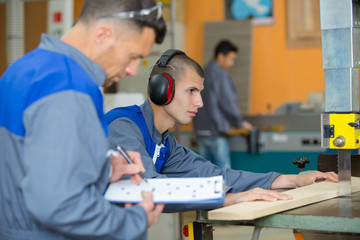 man evaluating a tradesman on her use of a jigsaw