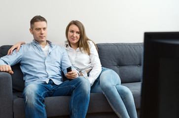 Man and woman watching TV at home.