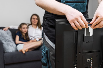 Man installing conditional access module card to TV.