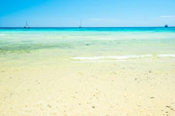 Fototapeta na wymiar White sand beach and clear sea water under blue sky