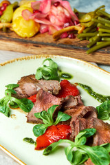 Carpaccio with sauce and spinach. Beautiful serving dishes. Light background. Restaurant menu