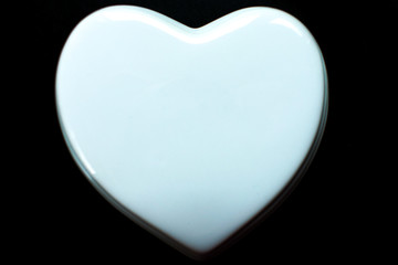 White glossy porcelain heart on a black background; postcard; Love note. Copy space